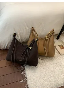 Close-up of brown and khaki hobo bags featuring gold hardware and logo on a cozy rug