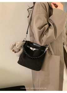 Detail of black matte bucket bag with silver turn-lock and plush rabbit charm
