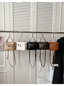 Multiple colors of minimalist box bags with silver zippers and top handles hanging in a row