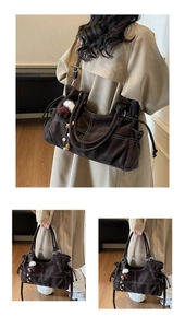 Detail showing high-capacity coffee tote bag with white contrast stitching and soft charms