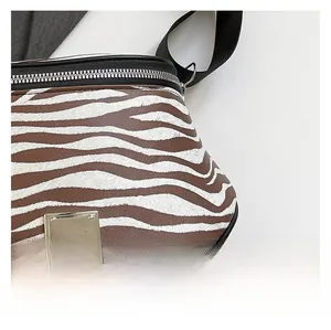 Nahaufnahme der Zebrastreifen-Textur und des silbernen Reißverschlusses an der Handtasche