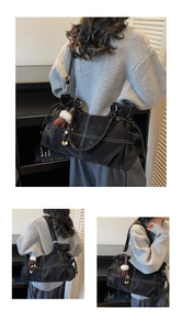 Detail of black leather tote bag with white stitching and plush bear pendant accessory