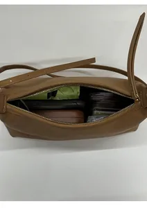 Internal view of brown leather shoulder bag showing storage for phone and cosmetics