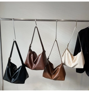 Hobo bags in black, brown, and cream displayed hanging on hooks in a minimalist setting