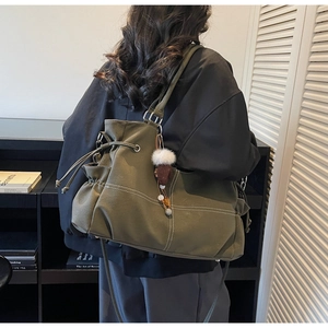 Detail of army green oversized leather tote bag with drawstring and cute bear charm