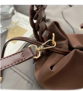 Detail of dark brown leather bucket bag with gold hardware hooks and pleated texture