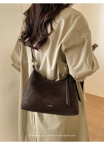 Detail of dark brown matte leather shoulder bag worn with a chic beige trench coat