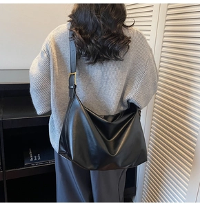 Detail showing the large black leather Hobo bag worn on the shoulder with wide strap