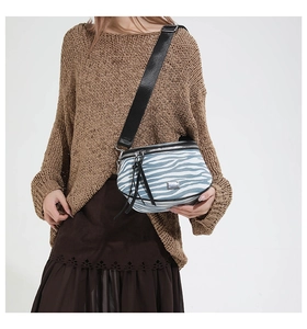 Detail der Satteltasche mit Zebramuster, blau-weißer Textur und breitem Schultergurt