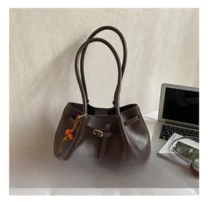 Détail du cabas en cuir mat marron foncé avec boucle métallique et gland en perles de bois