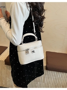 Detail of a white box bag with silver hardware and double zipper on a female model