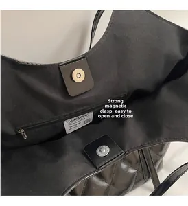 Detail showing the magnetic buckle closure and inner zipper pocket of the black tote bag
