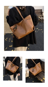Brown faux leather tote bag with tassel detail shown worn by a model in a park