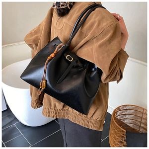 Détail du sac cabas vintage noir avec pompon en perles de bois et cuir synthétique