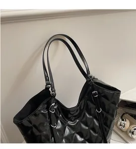 Detail of sturdy padded handles and silver hardware on black quilted leather tote bag