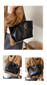 Macro shot of large black tote bag with textured faux leather and tassel detail