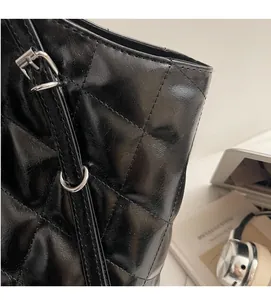 Close-up of black quilted tote bag showing soft leather texture and silver buckle detail