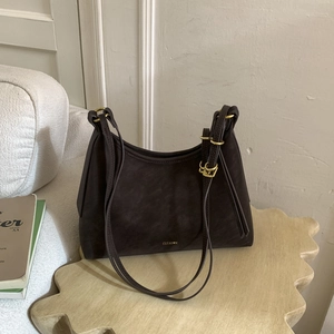 Close-up of matte dark brown leather shoulder bag featuring gold buckle and logo detail
