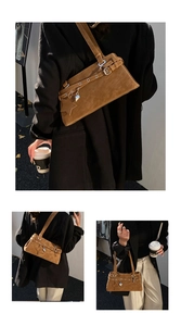 Nahaufnahme der braunen Wildleder-Schultertasche mit Silberringen und Sternanhänger
