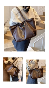 Close-up of large brown tote bag with litchi grain texture and tassel bead charm