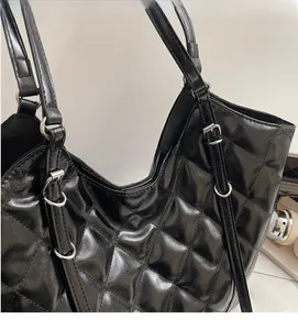 Close-up of black quilted faux leather tote bag showing silver metal rings and stitching
