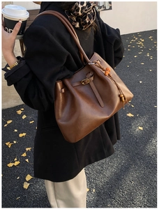 Détail du sac cabas vintage en cuir marron foncé avec des perles en bois orange élégantes