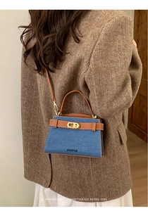 Detail of blue denim and brown leather crossbody bag with metallic rotary clasp closure