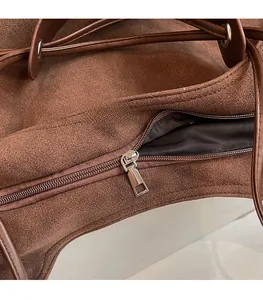 Detailed close-up of smooth silver zipper and brown faux suede texture on tote bag