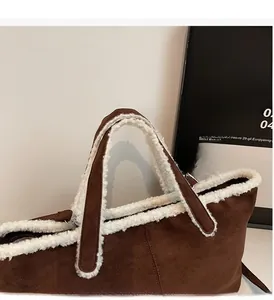 Detail of faux shearling trim and metal hardware on large brown crossbody handbag