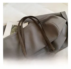Detail view of brown leather tote bag with heart charm and metallic eyelet strap