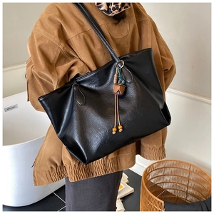 Detail of black faux leather tote bag with wooden bead tassel and double shoulder straps