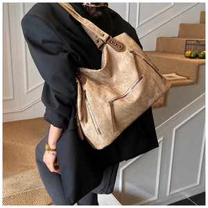 Détail du sac cabas rétro kaki avec fermetures éclair et rivets porté par un modèle