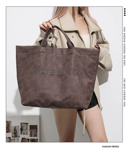 Detail shot of the rivet-patterned TOTE BAG text on a vintage brown leather bag