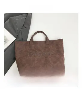 Detail view of brown vintage tote bag with rivet TOTE BAG lettering and retro texture