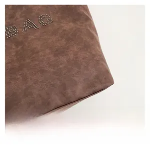 Close-up of brown vintage leather tote bag featuring metallic rivet decoration in BAG shape