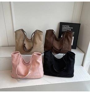 Close-up of suede tote bags in four colors arranged on white marble stairs