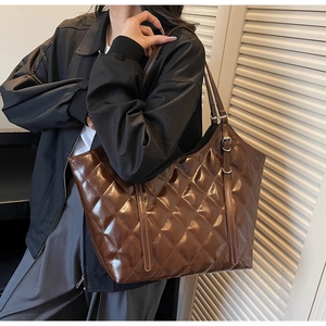 Detail of dark brown quilted tote bag with shiny finish and silver metal buckle strap