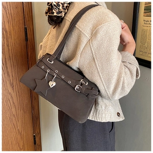 Close-up of vintage brown suede Boston bag featuring silver studs and star-heart charms
