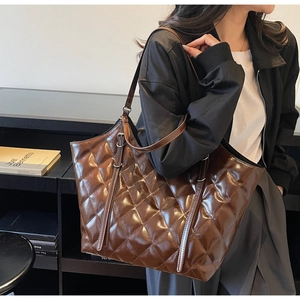 Close-up of brown quilted tote bag with diamond stitching and silver metal ring detail