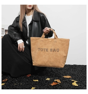 Macro detail of camel suede tote bag with perforated TOTE BAG logo text design