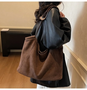 Detail of the large brown suede tote bag featuring reinforced stitching and metal eyelets