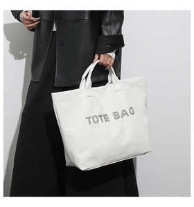 Detailed view of the large white tote bag showing bold TOTE BAG text and carrying handle
