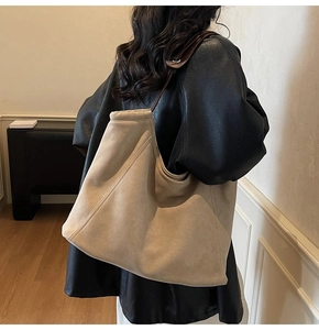 Detail of minimalist khaki suede tote bag with slim brown shoulder strap on model