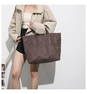 Detail of coffee brown tote bag with matte texture and TOTE BAG rivet design for women