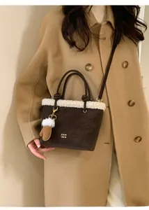 Detail of dark brown suede handbag with white faux fur trim and glove charm accessory
