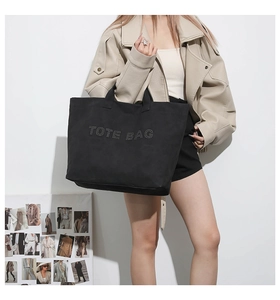 Close-up of silver metal rivets forming TOTE BAG text on a black tote handbag