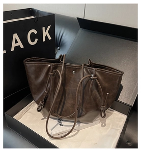 Detail of vintage dark brown leather tote bag with drawstring closure and silver rivets