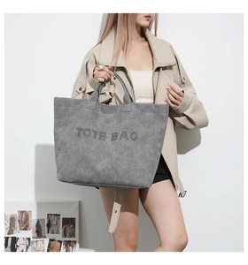 Detail of grey suede tote bag with metal rivet TOTE BAG lettering and sturdy handles