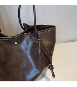 Close-up of deep brown oil wax leather texture and silver metal eyelets on tote bag