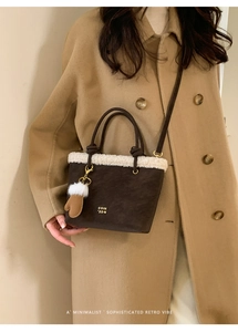 Detail of winter tote bag with white faux fur trim and gold lettering on brown suede